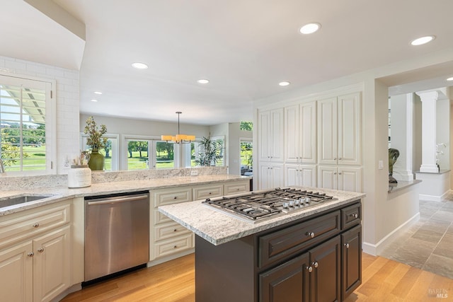 kitchen featuring stainless steel appliances, a chandelier, recessed lighting, light stone counters, and a sink