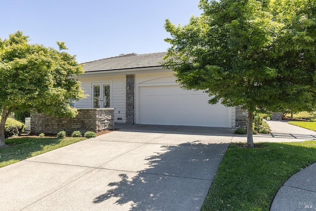 view of front of home featuring stone siding, driveway, an attached garage, french doors, and a tile roof