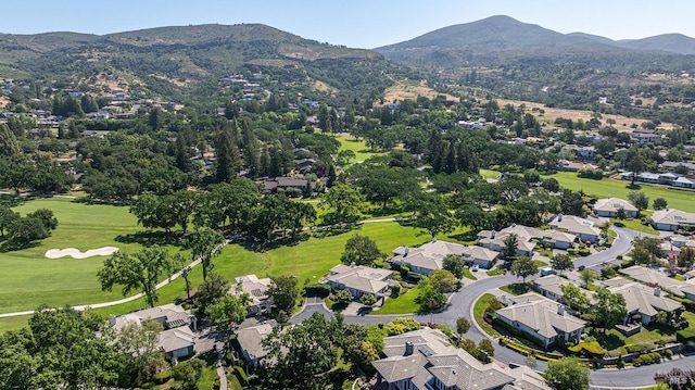 aerial view of property and surrounding area featuring mountains, nearby suburban area, and a golf club