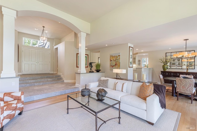 living area with decorative columns, light wood-style flooring, recessed lighting, and arched walkways