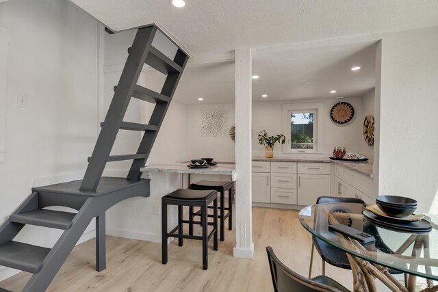 1575 Felder Rd, Sonoma, CA 95476 - kitchen featuring light wood-style floors, white cabinetry, light countertops, a breakfast bar area, and recessed lighting