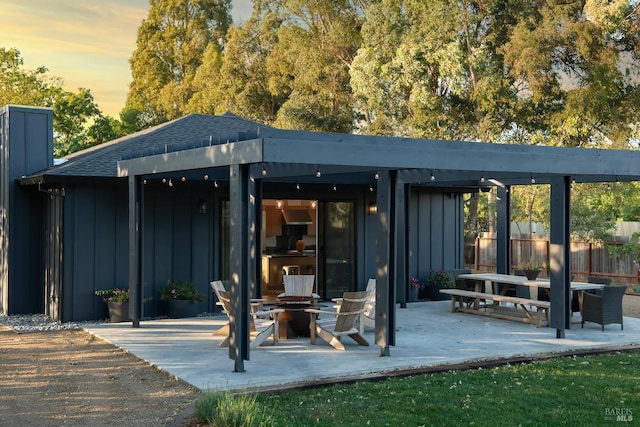 1575 Felder Rd, Sonoma, CA 95476 - back of house at dusk featuring board and batten siding, a fire pit, fence, a patio, and a chimney