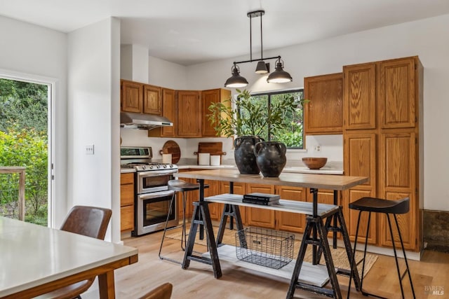 16 Ivy Ln, Woodacre, CA 94973 - kitchen with range with two ovens, under cabinet range hood, light wood-type flooring, light countertops, and brown cabinetry