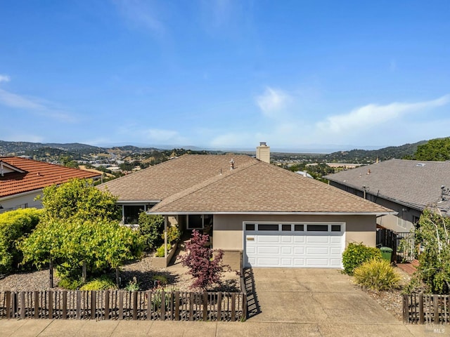 ranch-style home with concrete driveway, fence, a shingled roof, a garage, and stucco siding