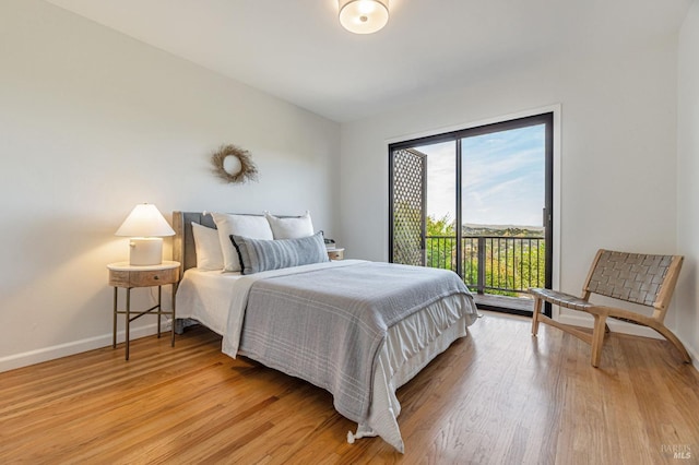 bedroom featuring access to outside, baseboards, and light wood-type flooring