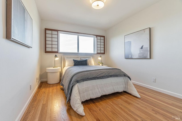 bedroom featuring light wood finished floors and baseboards