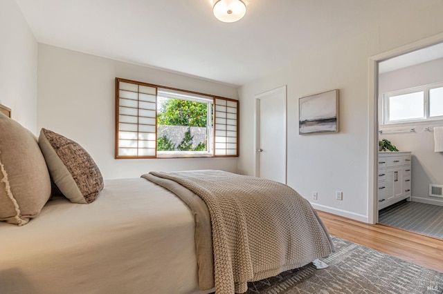 bedroom with wood finished floors, multiple windows, and baseboards