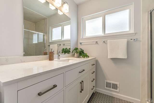 full bathroom with a stall shower, vanity, baseboards, and tile patterned floors