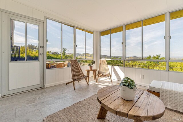 sunroom / solarium featuring a mountain view, stone finish floors, and a decorative wall