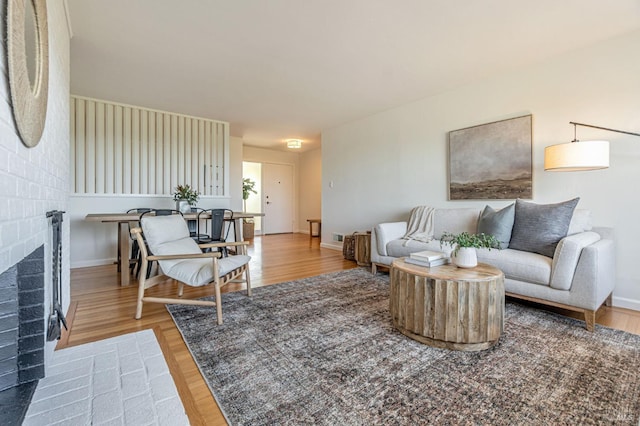 living area with a brick fireplace, wood finished floors, and baseboards