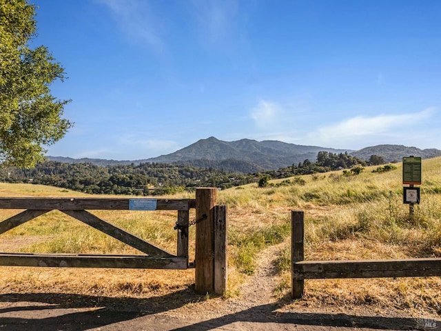 gate with a mountain view, fence, and a view of rural / pastoral area