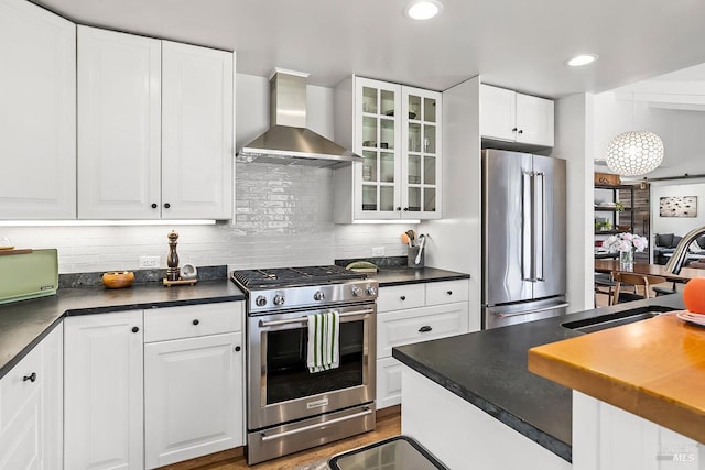 229 Cardinal Rd, Mill Valley, CA 94941 - kitchen with stainless steel appliances, wall chimney exhaust hood, dark countertops, glass insert cabinets, and white cabinetry