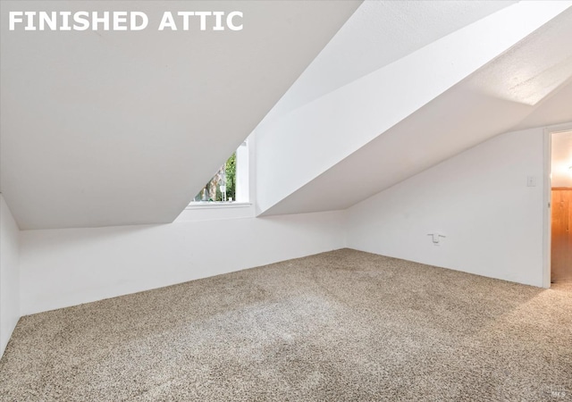 bonus room with carpet flooring and vaulted ceiling