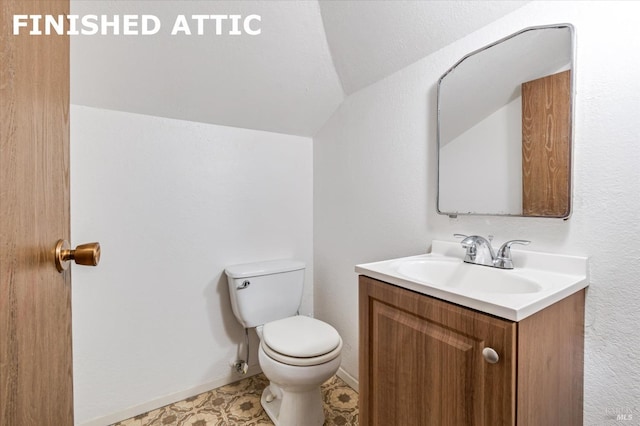 half bathroom with toilet, vanity, and vaulted ceiling