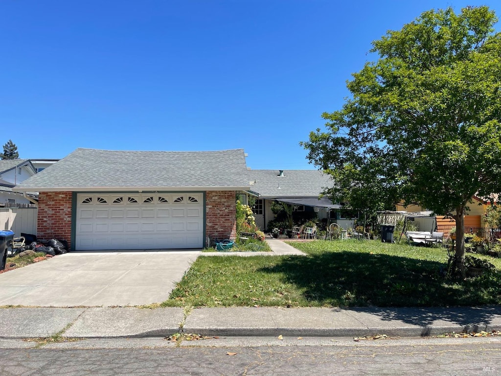 view of front of home featuring driveway, an attached garage, a front yard, and brick siding