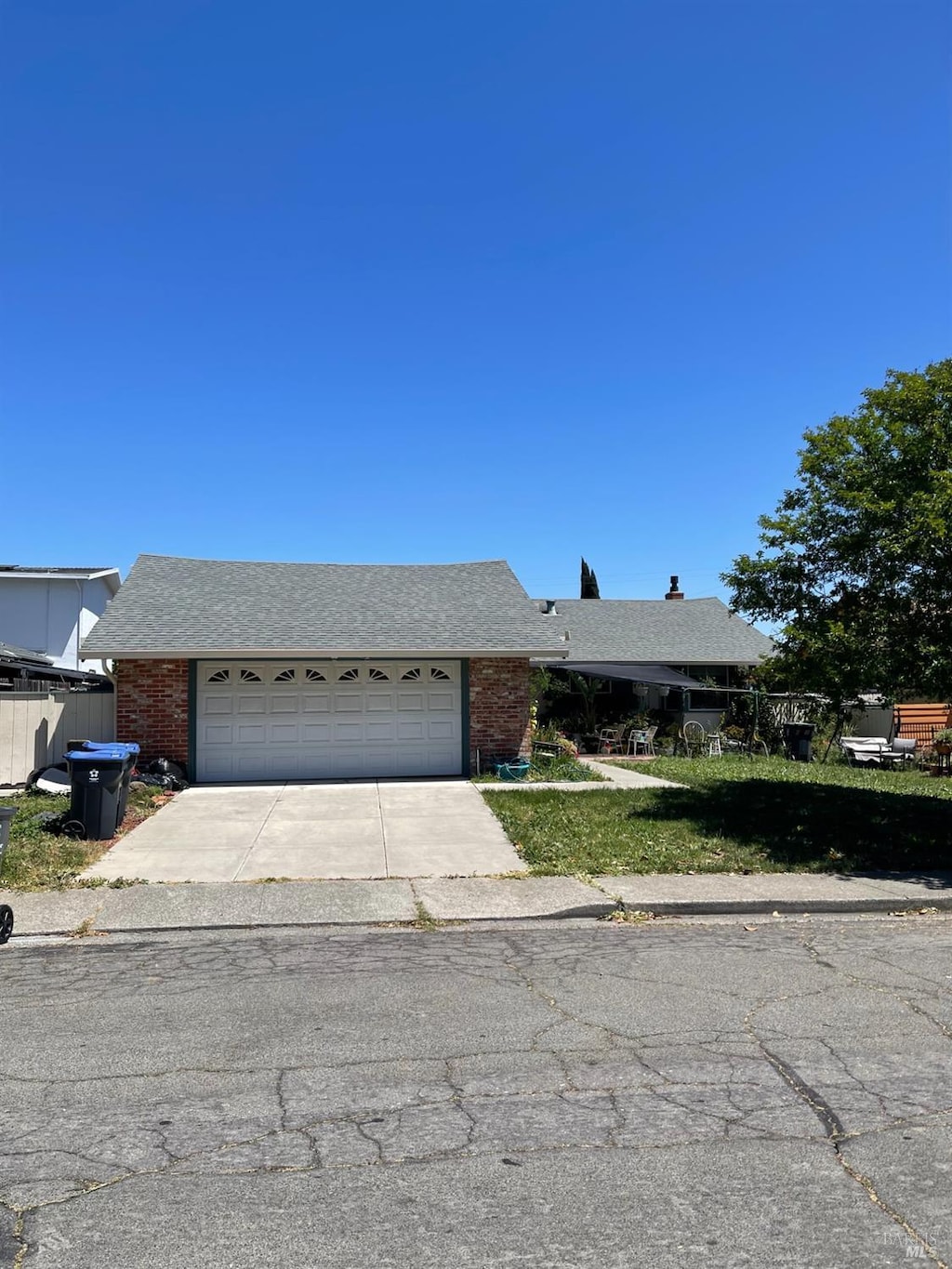 view of front of home featuring driveway, an attached garage, brick siding, and roof with shingles