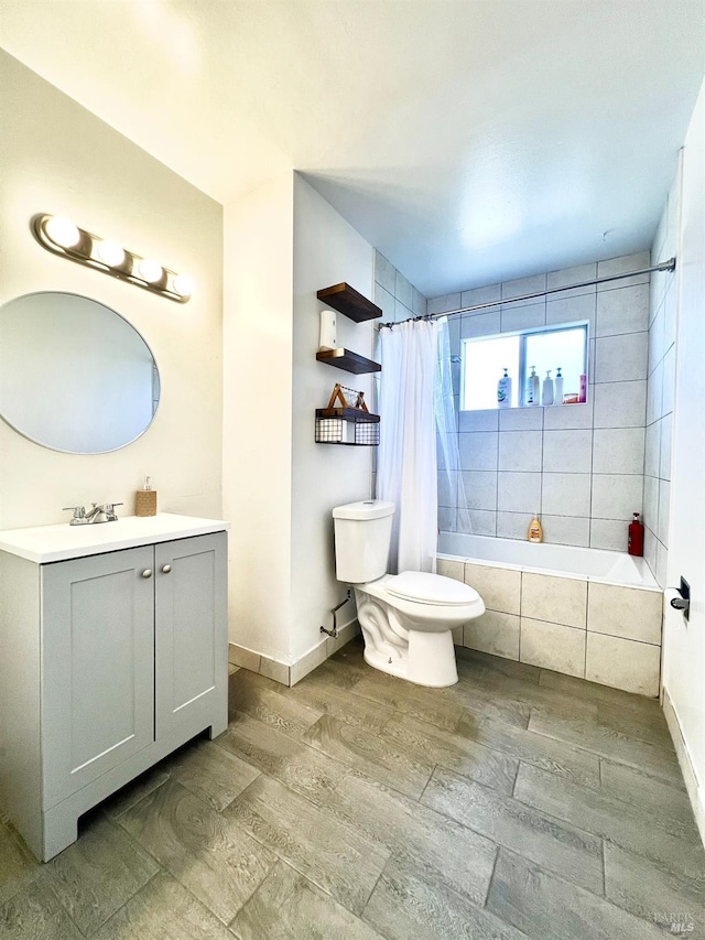 full bath with wood finished floors, tiled shower / bath, toilet, baseboards, and vanity