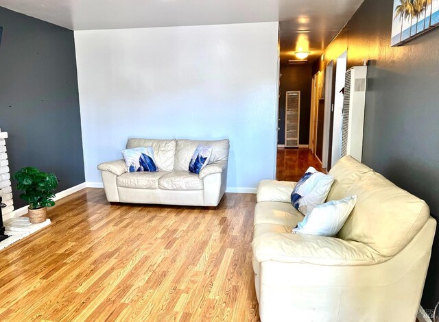 living room with wood finished floors, baseboards, and a heating unit