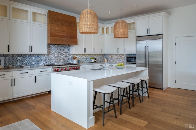 421 Crown Rd, Kentfield, CA 94904 - kitchen with stainless steel appliances, a sink, wood finished floors, decorative backsplash, and a center island with sink