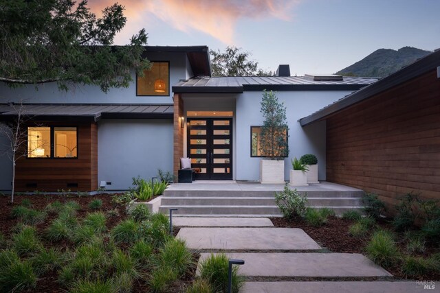 421 Crown Rd, Kentfield, CA 94904 - exterior entry at dusk featuring a standing seam roof, stucco siding, and metal roof