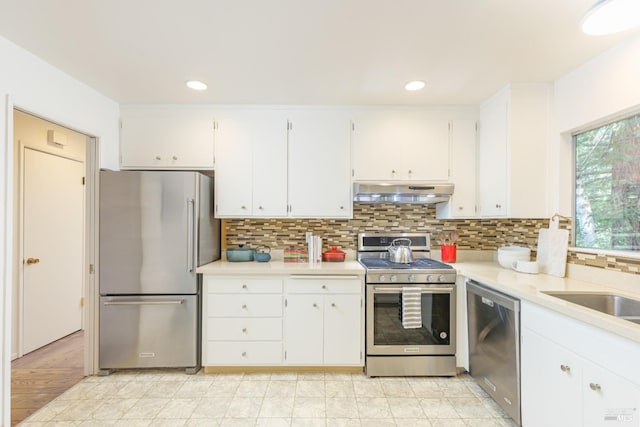 kitchen with appliances with stainless steel finishes, under cabinet range hood, white cabinets, light countertops, and recessed lighting