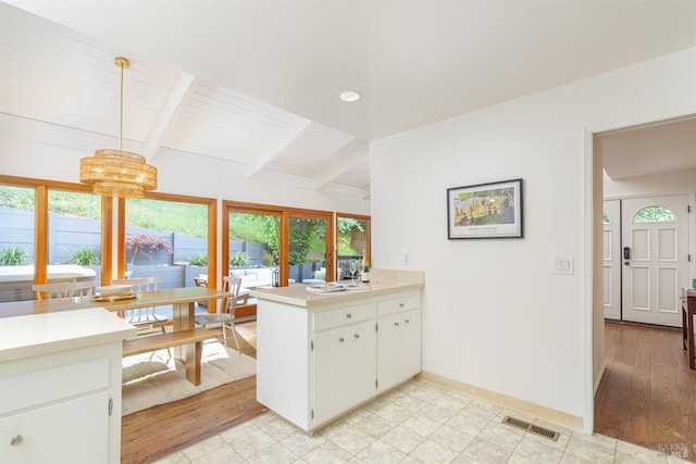 kitchen featuring light countertops, a peninsula, baseboards, white cabinets, and a chandelier