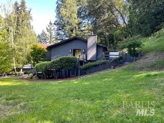 view of side of home with a yard and a chimney