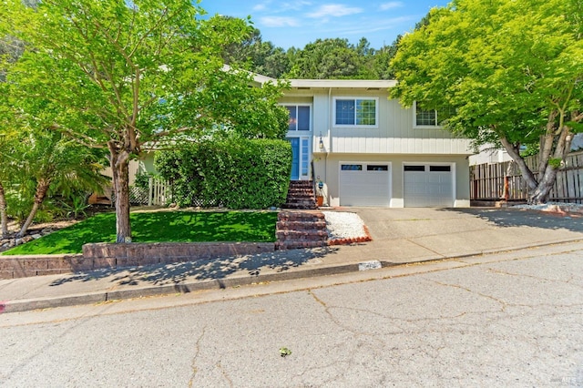 raised ranch with fence, driveway, and a garage