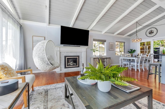 living area featuring a chandelier, wood finished floors, a premium fireplace, healthy amount of natural light, and beam ceiling