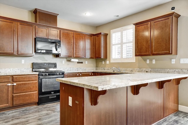 566 Chaparral Loop, Vacaville, CA 95688 - kitchen with black appliances, light wood finished floors, a kitchen breakfast bar, a peninsula, and brown cabinetry
