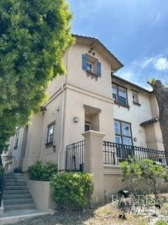 view of front of home with stucco siding and stairway
