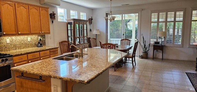611 Twin Lakes Ln, Rio Vista, CA 94571 - kitchen featuring a sink, a wall mounted air conditioner, stainless steel range with gas cooktop, tasteful backsplash, and an island with sink
