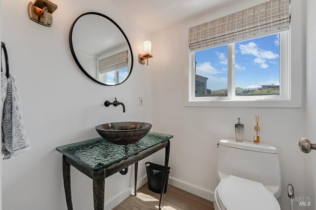 bathroom with a sink, baseboards, toilet, and wood finished floors