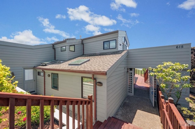 rear view of house with a shingled roof and a wooden deck