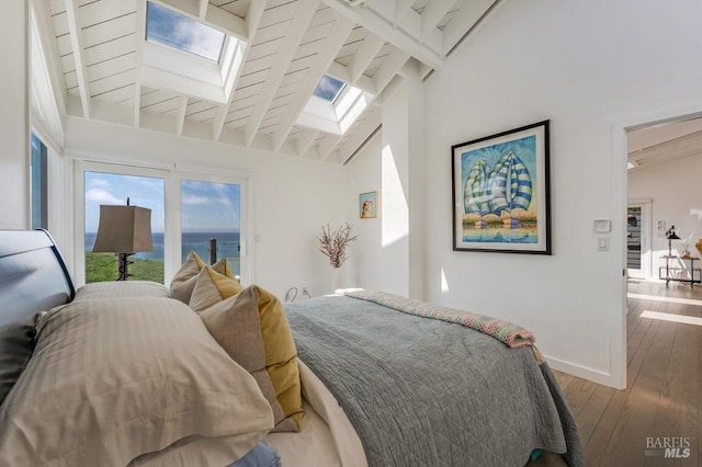 bedroom with a skylight, wood finished floors, baseboards, access to outside, and a water view