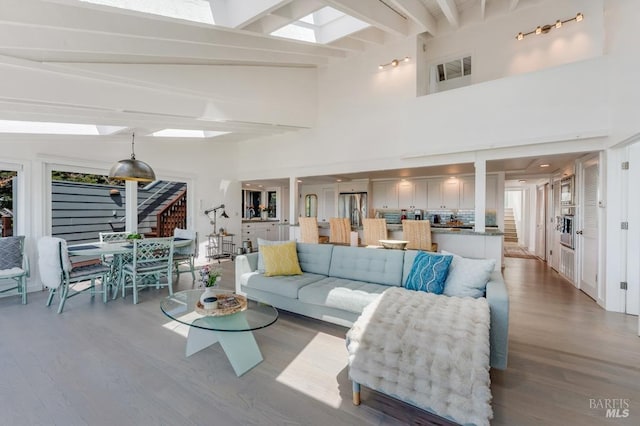 living area featuring beam ceiling, wood finished floors, and a high ceiling