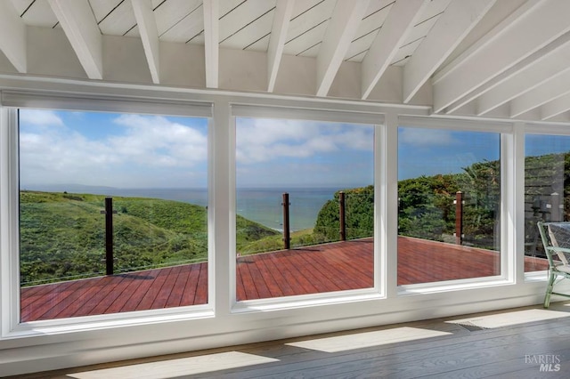 unfurnished sunroom featuring a water view and beamed ceiling