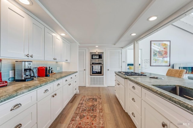 kitchen featuring stainless steel appliances, recessed lighting, white cabinetry, light stone countertops, and light wood finished floors