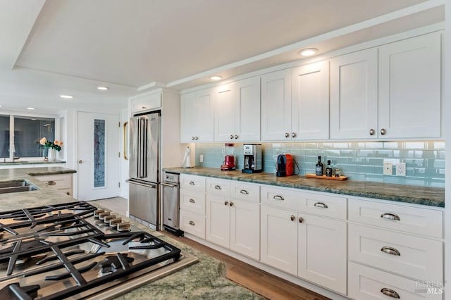 kitchen with stainless steel appliances, white cabinets, tasteful backsplash, recessed lighting, and dark stone countertops