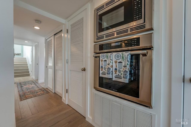 hall with wood finished floors, stairs, recessed lighting, and baseboards