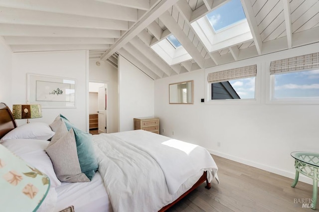 bedroom featuring a skylight, wood finished floors, and baseboards