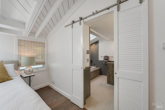 bedroom with a barn door, baseboards, and wood finished floors