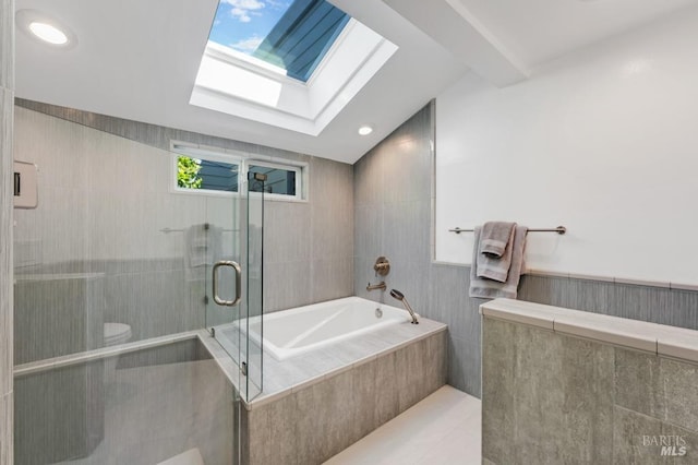full bath with a shower stall, a bath, a skylight, and tile walls