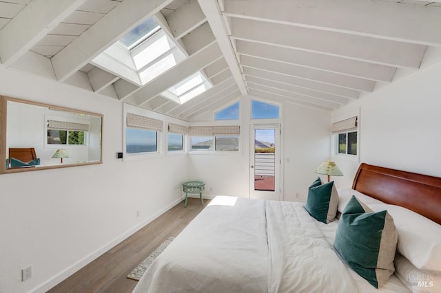 bedroom with a skylight, wood finished floors, baseboards, and access to outside