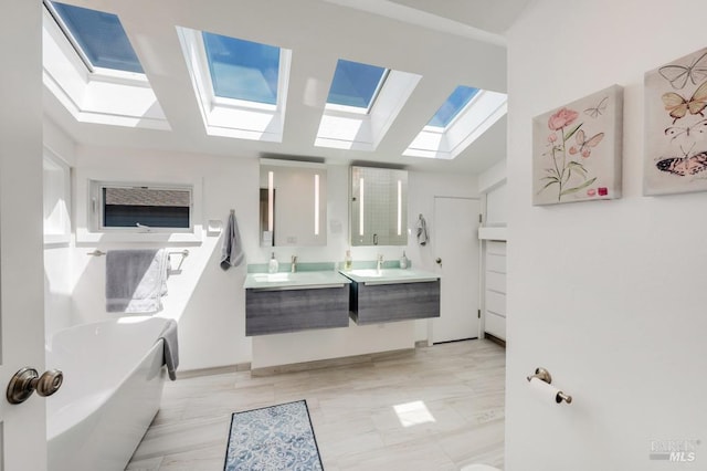bathroom featuring a skylight, double vanity, and a bathtub