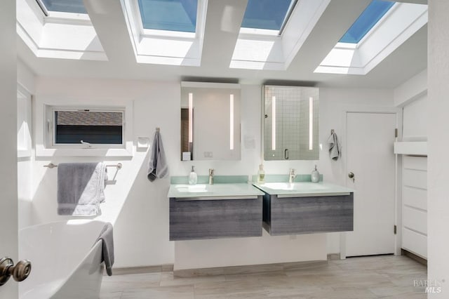 bathroom featuring a skylight, two vanities, and a tub to relax in