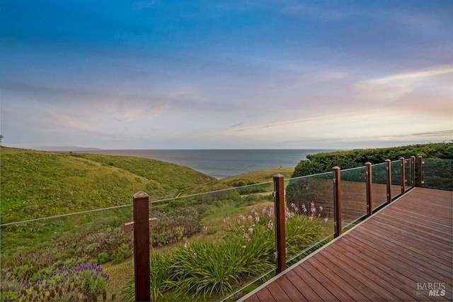 deck at dusk featuring a water view
