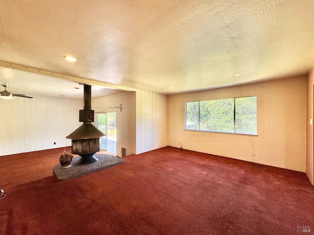 4511 Dry Creek Rd, Napa, CA 94558 - unfurnished living room featuring carpet flooring, a wood stove, plenty of natural light, a textured ceiling, and ceiling fan