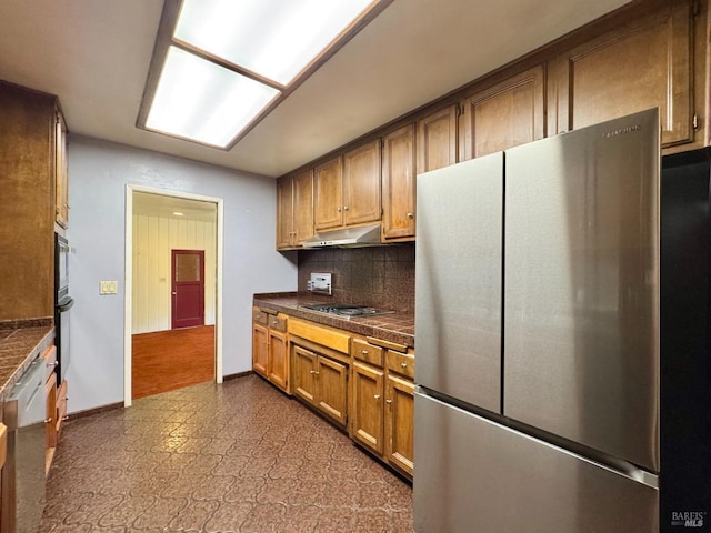 4511 Dry Creek Rd, Napa, CA 94558 - kitchen featuring appliances with stainless steel finishes, dark countertops, decorative backsplash, under cabinet range hood, and brown cabinetry