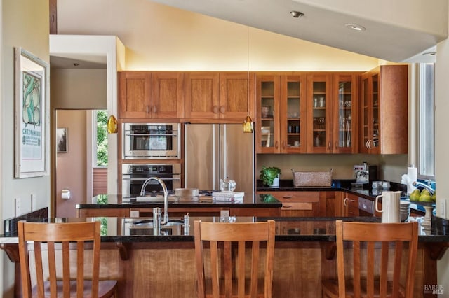 1 Dover Rd, Inverness, CA 94937 - kitchen featuring stainless steel appliances, brown cabinets, lofted ceiling, glass insert cabinets, and dark stone counters